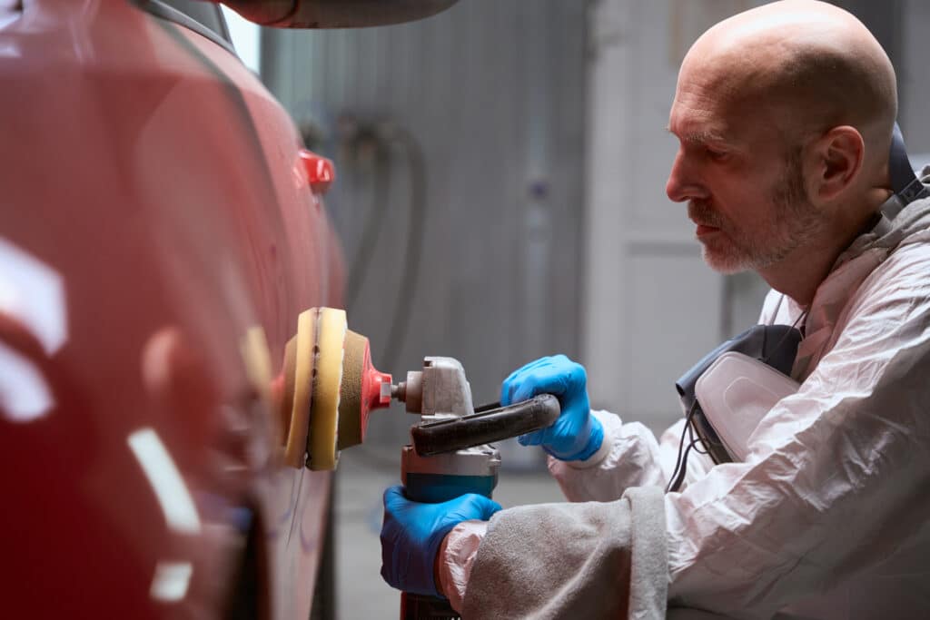 A man buffing a car at a collision center repair shop in Delray Beach, FL