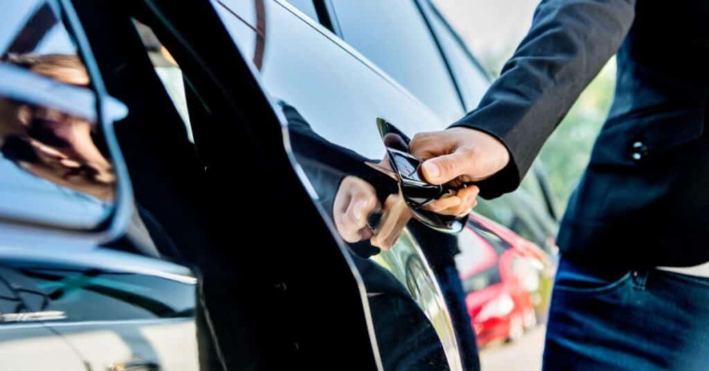 Person opening a black car door — highlighting potential door ding areas on the side panel