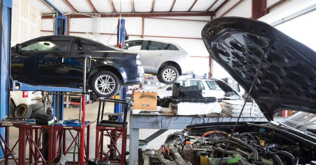 Busy auto body repair facility with multiple vehicles being serviced.