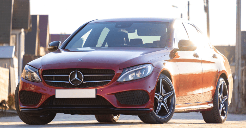 Front view of a sleek red Mercedes-Benz C-Class sedan parked outdoors, showcasing perfect paint finish and body alignment.